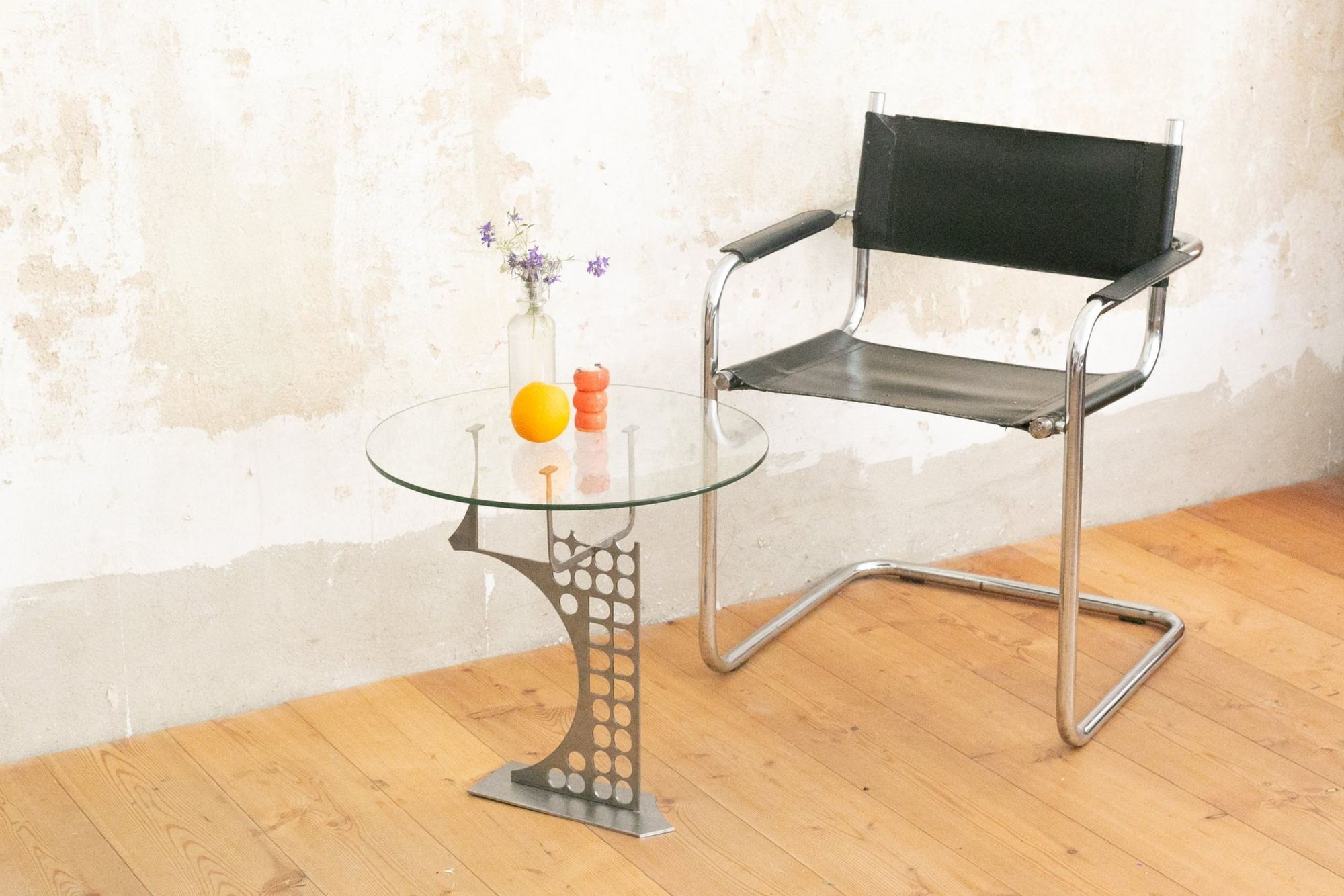 Beistelltisch mit Glasplatte neben einem Stuhl vor einer Wand